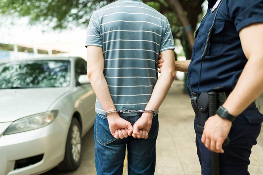A man is handcuffed by a policeman